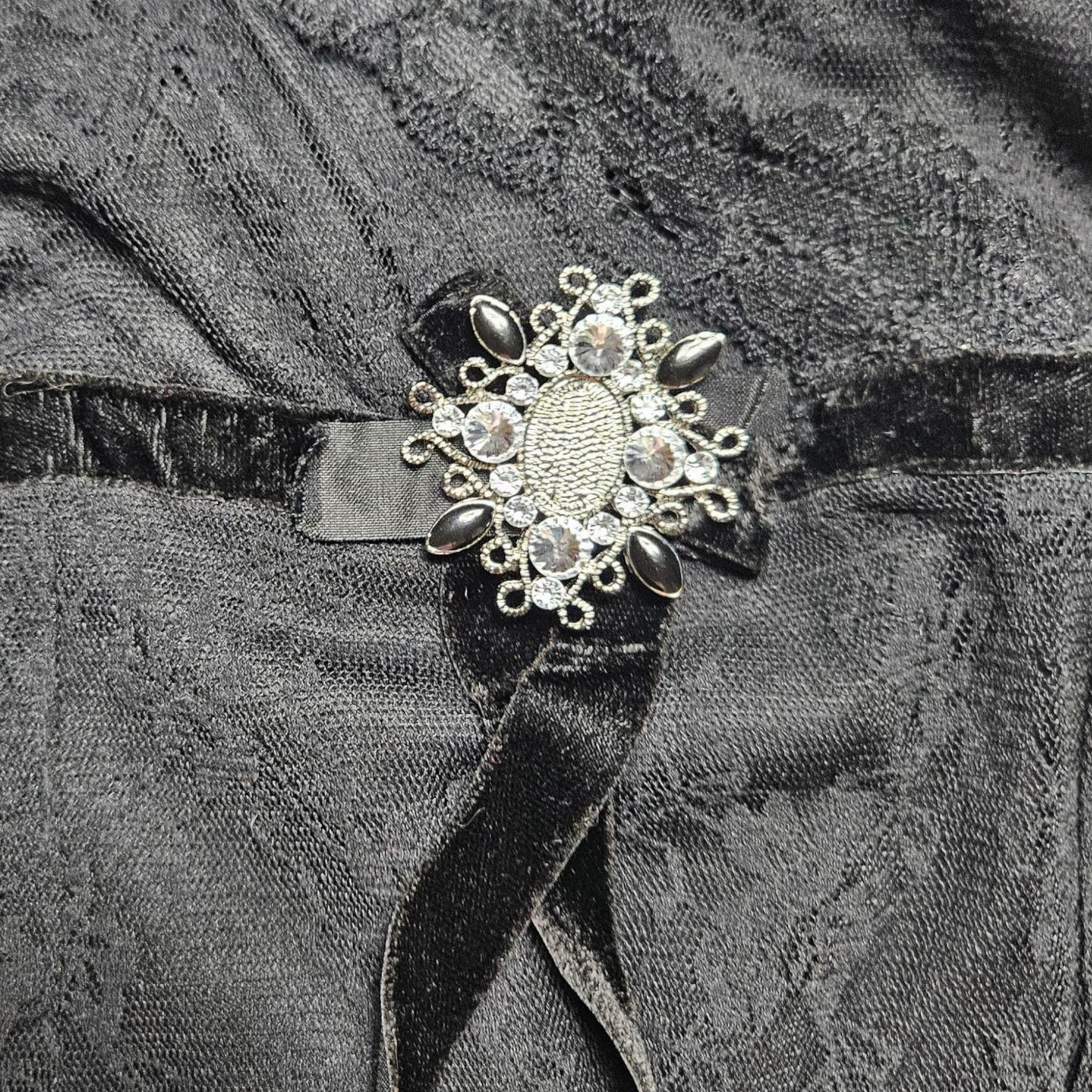 Haut asymétrique noir en dentelle avec broche