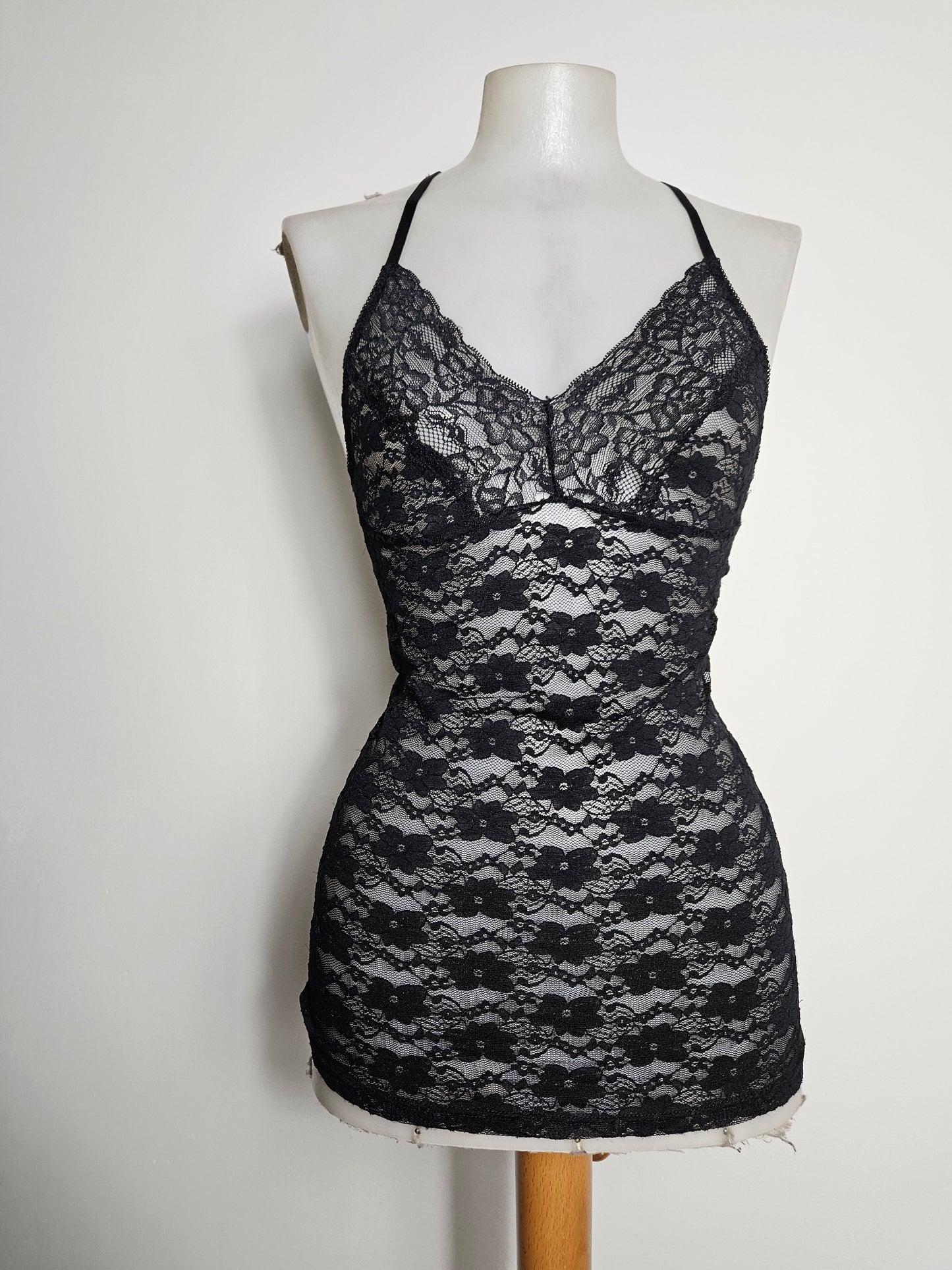 A sultry Y2K-inspired sheer black lace camisole featuring a delicate floral pattern, thin spaghetti straps, and a romantic racerback lace detail for a perfect whimsigoth or dark coquette aesthetic.