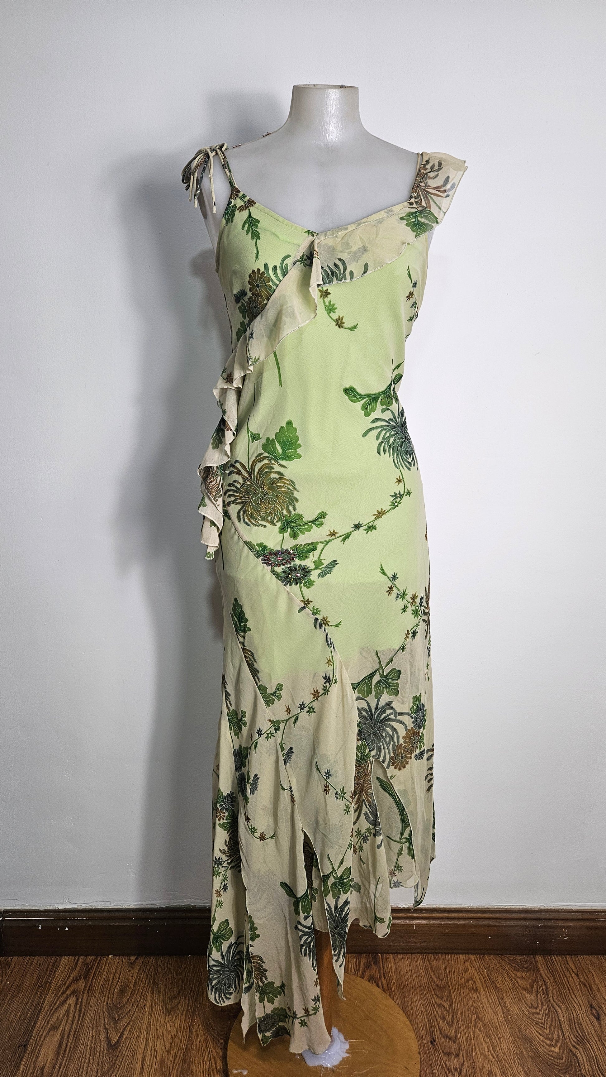 Vintage lime green midi dress with floral botanical print, asymmetric ruffled hem, and sheer chiffon layers on a mannequin. Y2K fairycore style.