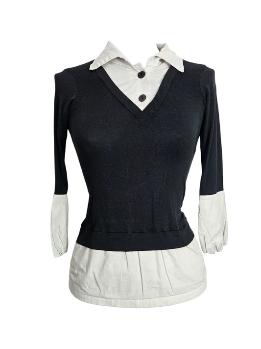 Black v-neck sweater layered over white collared shirt. 2-in-1 long sleeve top with button details on mannequin. Minimalist dark academia aesthetic.