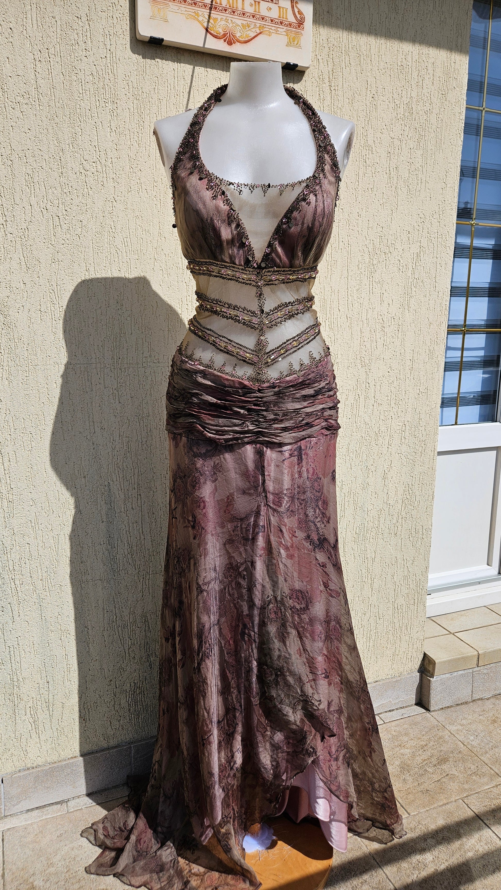 Mauve halter neck mermaid gown with sheer beaded midriff, floral print overlays, and sequins. Elegant vintage evening dress for prom or formal galas.