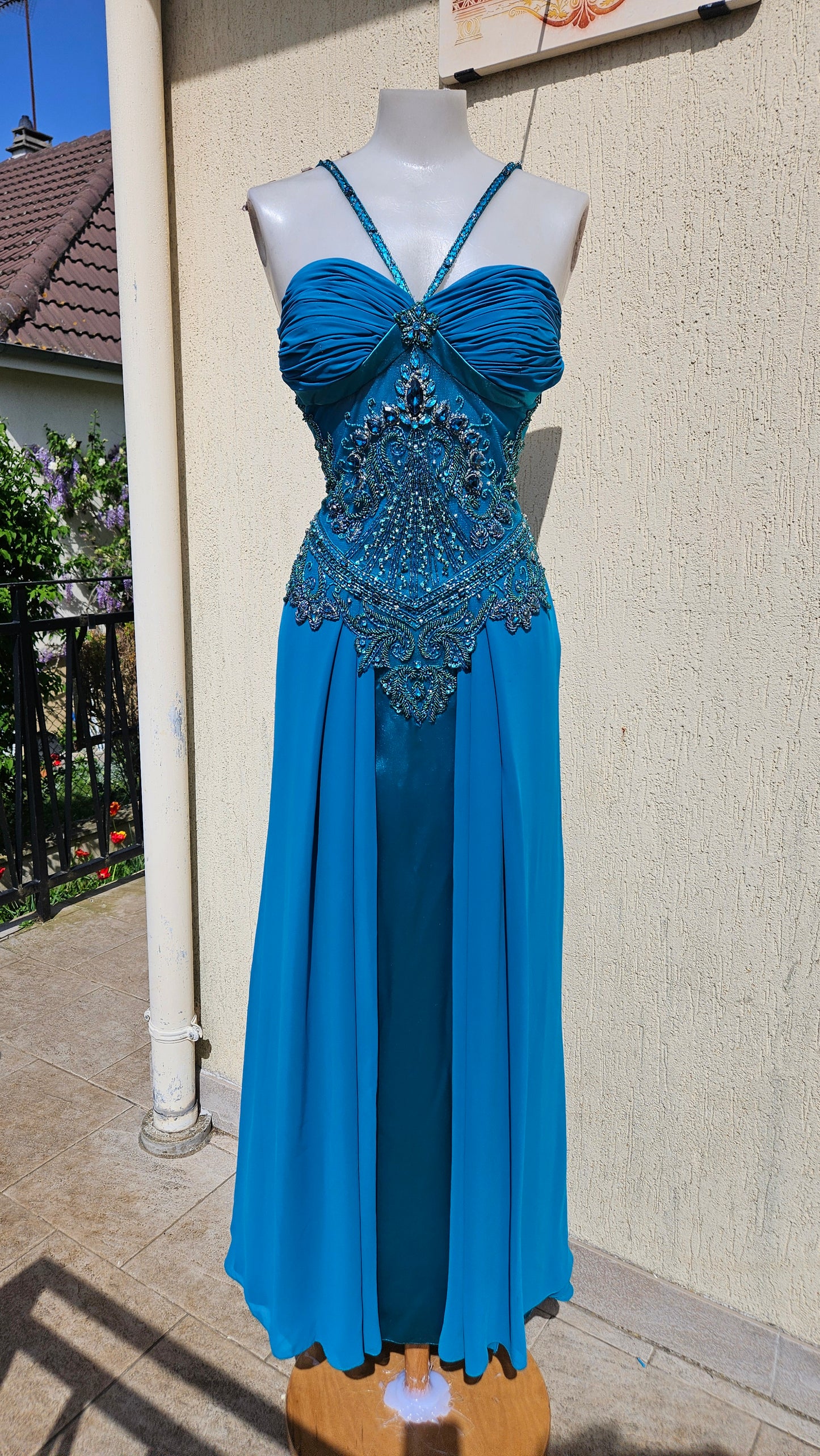 Turquoise blue chiffon evening gown with halter neck, pleated bust, and ornate teal bead & crystal bodice embroidery. Elegant mermaid style formal dress.