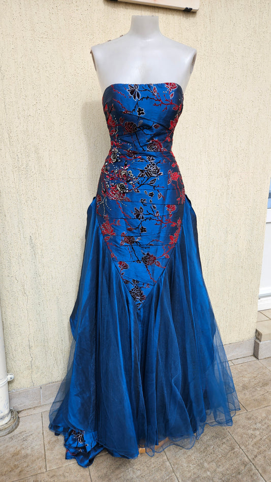 Strapless royal blue evening gown with red and black floral embroidery, sequined bodice, and a voluminous tulle mermaid skirt for formal galas or prom.