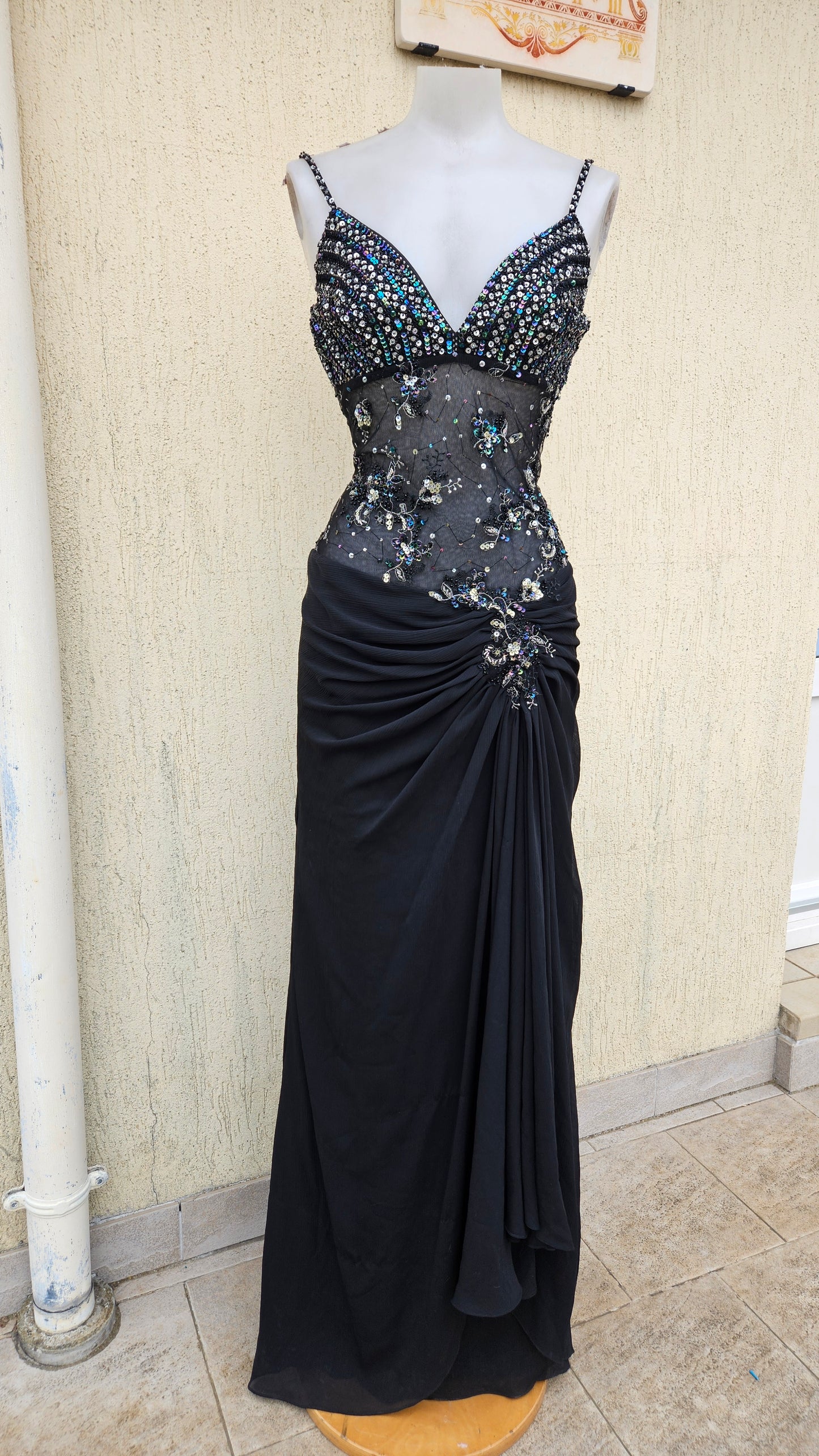 Vintage Y2K black maxi gown on a mannequin with a sequined bodice, sheer beaded midriff, and elegant side-draped skirt. Perfect for formal events or prom.