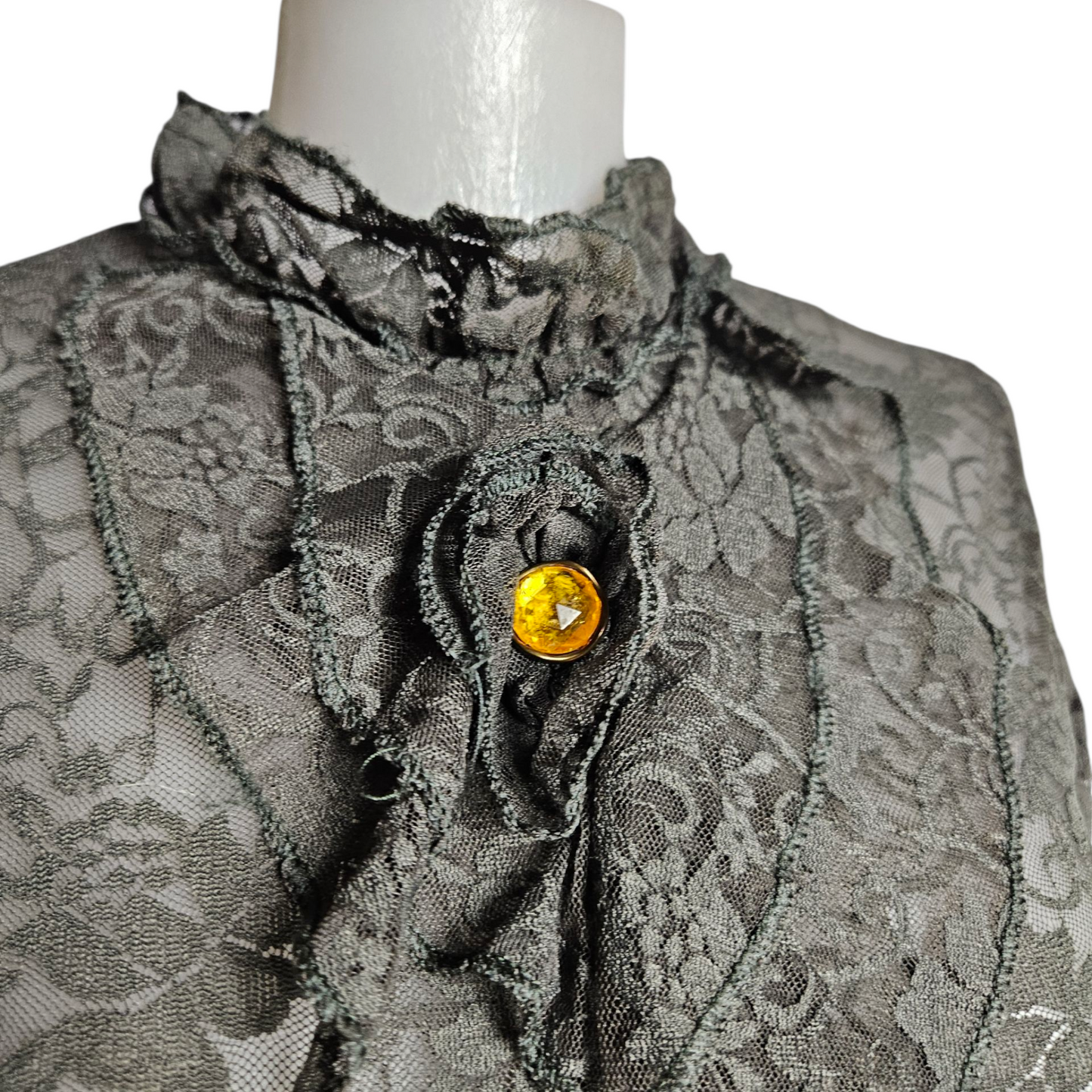 Lace blouse with ruffle details and brooch