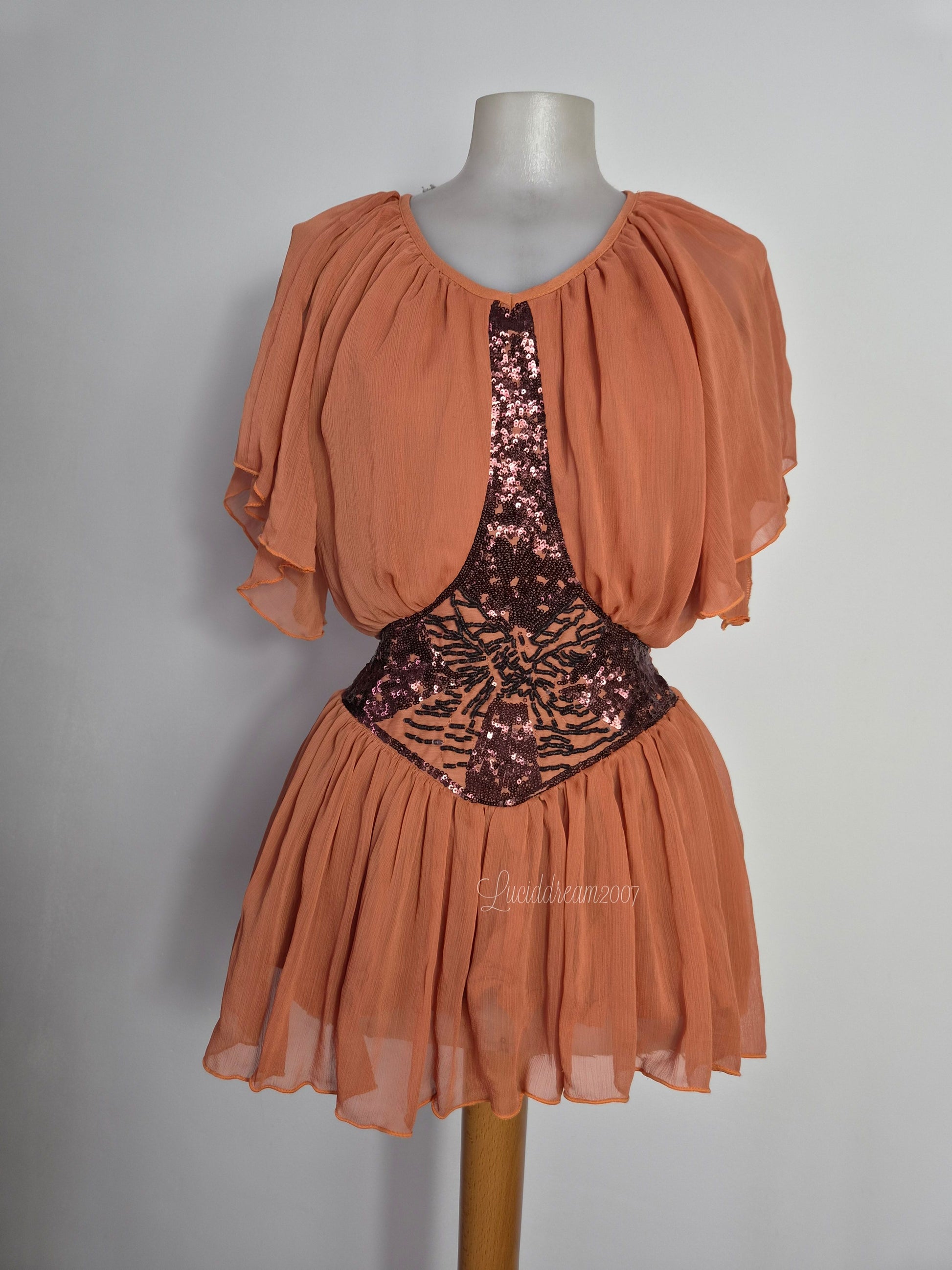 Chemisier vintage bohème chic en mousseline pêche avec des détails complexes de sequins et de perles sur le corsage. Style fairycore romantique et fluide. sorti d'une reverie vintage