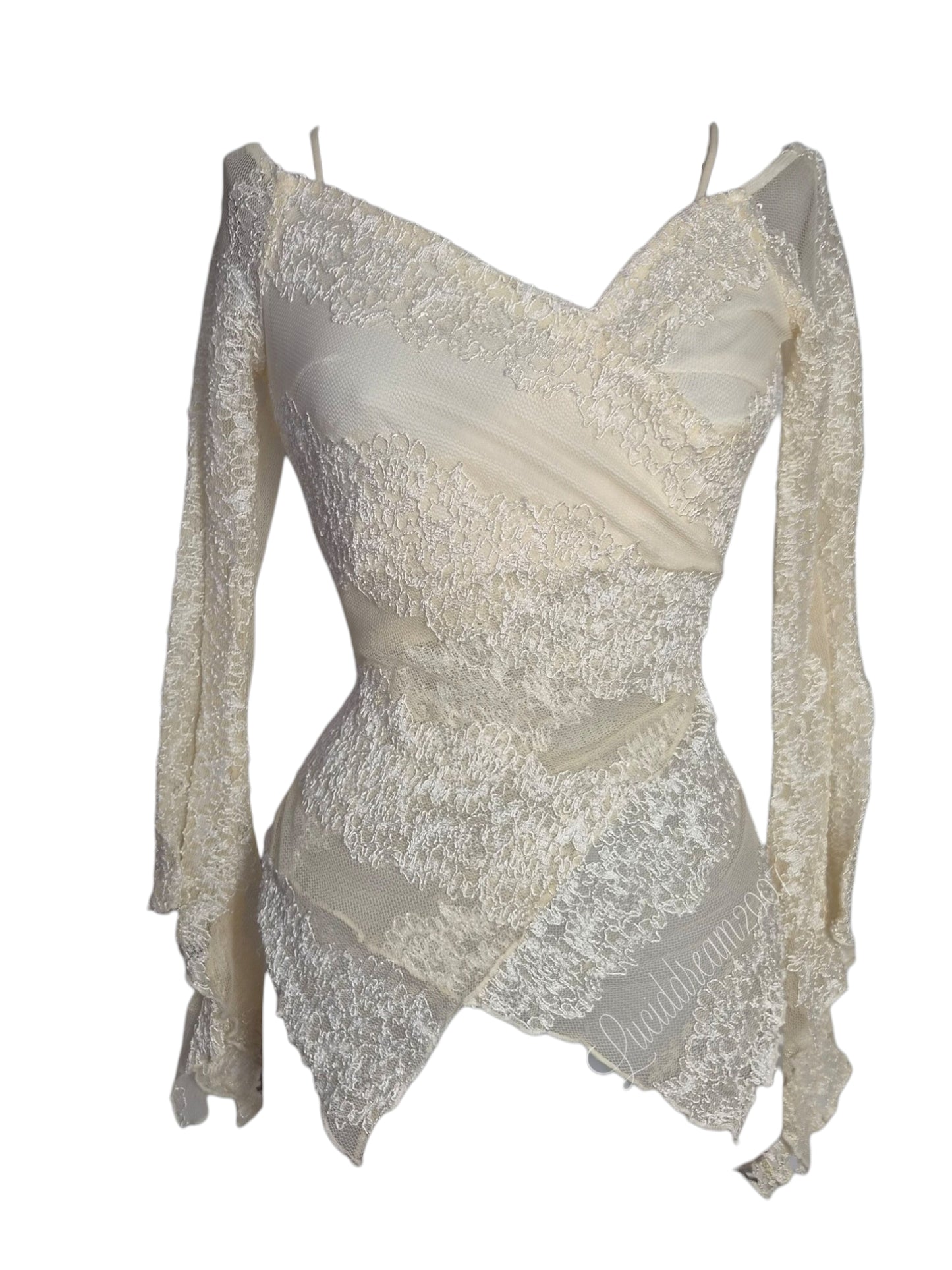 Haut vintage à manches longues de couleur crème / blanc cassé.
Avec une coupe asymétrique, avec des superpositions de tissus mêlant des empiècements opaques à des parties en dentelle travaillée. Dasn le style fairycore coquette qsorti d'une reverie